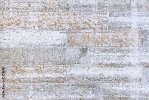 The wall is made of yellowish blocks of hewn limestone. Facing material made of natural stone.