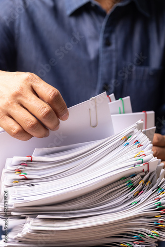 Vertical male office workers holding and writing documents on office desk, Stack of business overload paper.