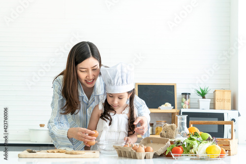 A young girl and daughter learned to cook breakfast with mom. A beautiful Asian woman was happy in the kitchen at home. 