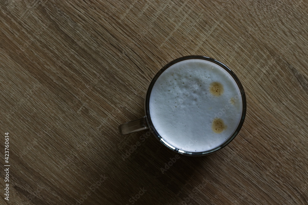 A cup with coffee on a wooden table in the room, made with a coffee machine A cup with coffee on a wooden table in the room, made with a coffee machine