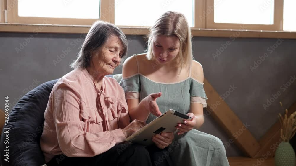 Daughter teaches an elderly woman to use the tablet and new skills. Teaching the elderly with modern technology Daughter teaches an elderly woman to use the tablet and new skills. Teaching the elderly with modern technology