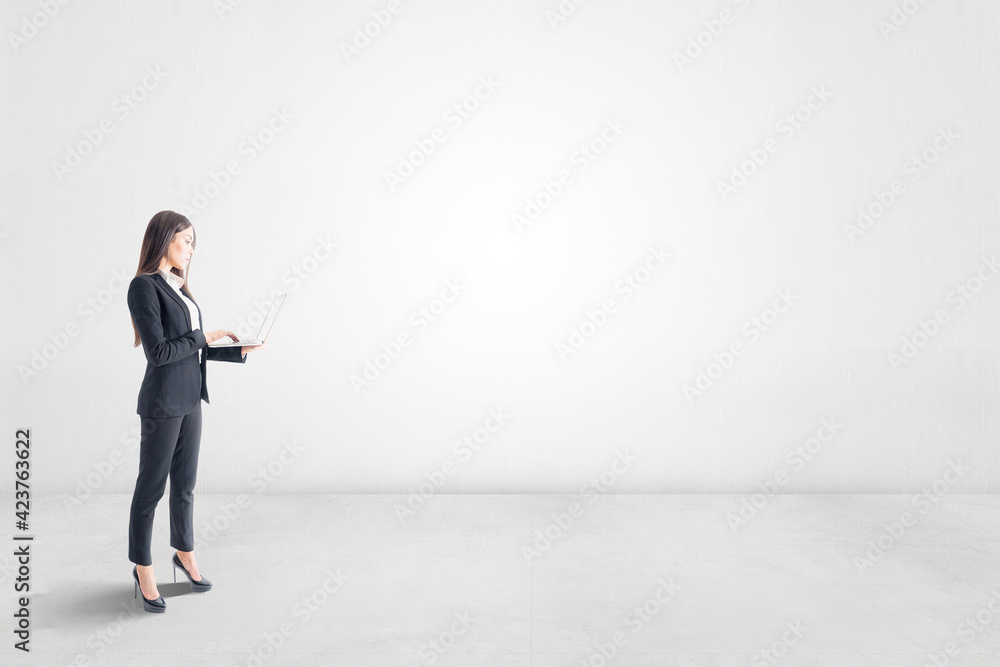 New idea and thinking about future concept with businesswoman with laptop in empty light room with blank wall. Mockup New idea and thinking about future concept with businesswoman with laptop in empty light room with blank wall. Mockup