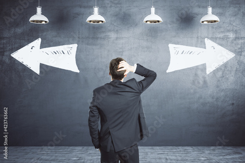 Cuadro en lienzo Choice concept with businessman looking at black wall with handwritten opposite looking arrows