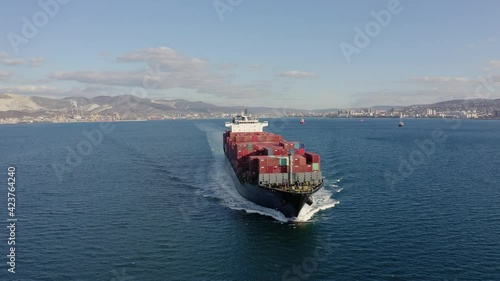 Ultra large loaded container ship cruising in open ocean, aerial view. High quality 4k drone footage of Cargo ship departing from the port. Concept of freight transportation, import export business