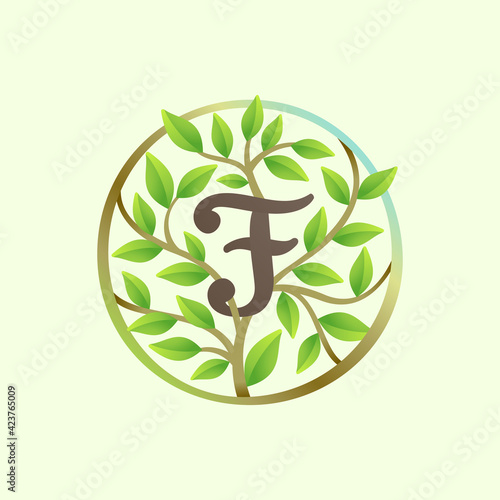 F letter logo made of twisted tree branches and green leaves in circle.