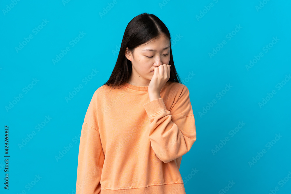 Young Chinese girl over isolated blue background having doubts Young Chinese girl over isolated blue background having doubts
