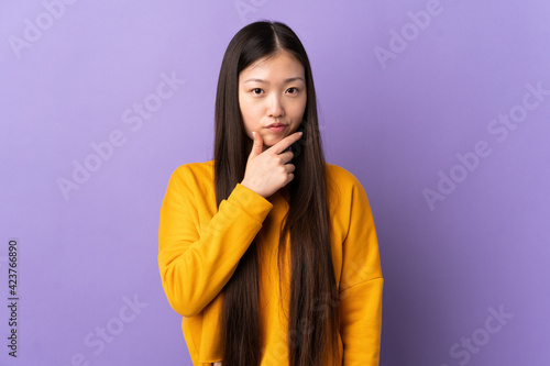 Young Chinese girl over isolated purple background thinking