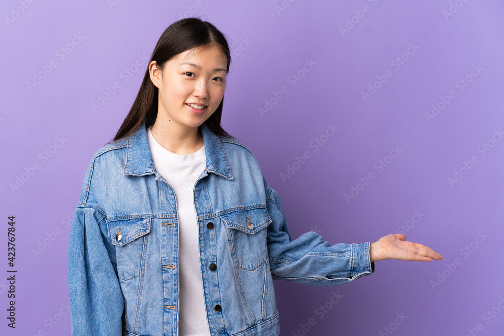 Young Chinese girl over isolated purple background extending hands to the side for inviting to come Young Chinese girl over isolated purple background extending hands to the side for inviting to come