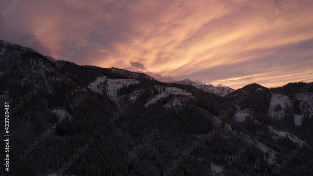 Aerial view moving forward shot, Scenic view of mountain range covered in snow and pine trees in Styria, Austria, scenic view sunrise in the background. Aerial view moving forward shot, Scenic view of mountain range covered in snow and pine trees in Styria, Austria, scenic view sunrise in the background.