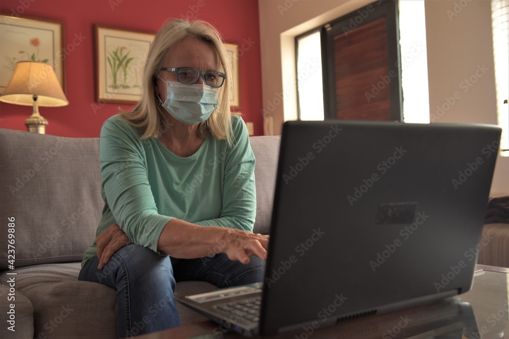 A woman sits in front of her laptop at home, talking with colleagues on a video call and watching content online A woman sits in front of her laptop at home, talking with colleagues on a video call and watching content online