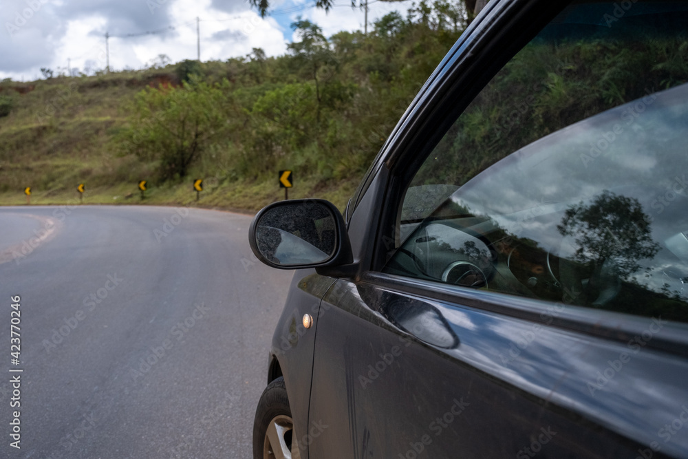 Carro preto parado a beira da estrada, com o vidro semiaberto, no interior de Minas Gerais