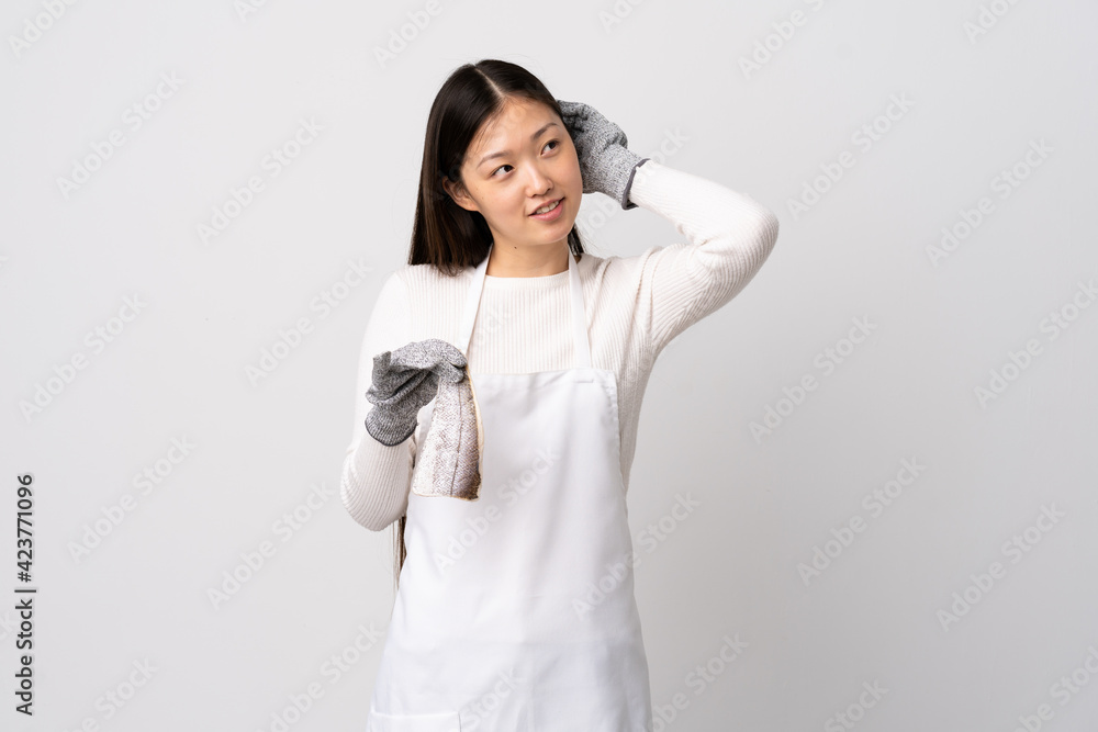 Chinese fishmonger wearing an apron and holding a raw fish over isolated white background thinking an idea Chinese fishmonger wearing an apron and holding a raw fish over isolated white background thinking an idea
