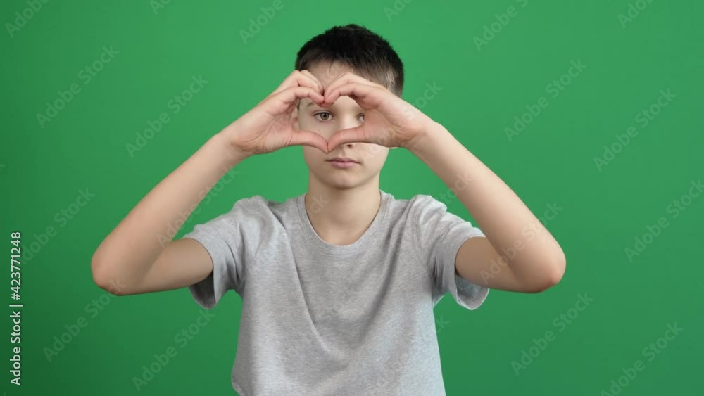 Boy hands making heart shape gesture on green screen chromakey background. Person forms heart shape using their fingers Boy hands making heart shape gesture on green screen chromakey background. Person forms heart shape using their fingers