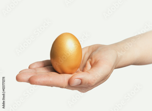 Golden egg in a woman's palm. Concept of luxury, individuality; best choice. Isolated on white.