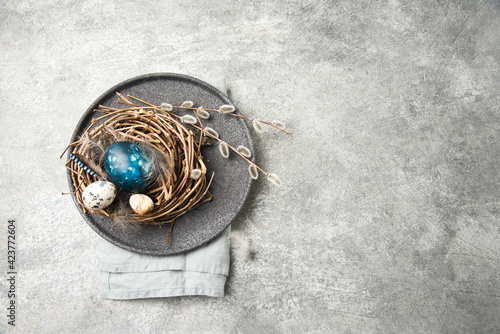 Easter nest with eggs, feathers and pussy willow twigs on a natural stone background. space for text