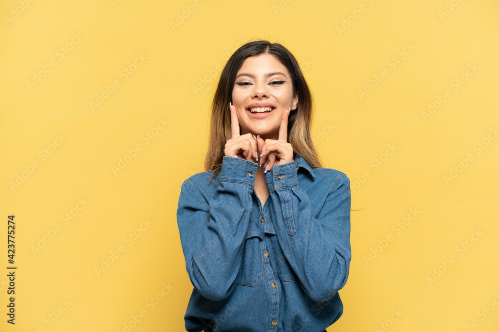 Young Russian girl isolated on yellow background smiling with a happy and pleasant expression