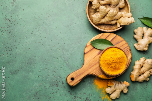 Composition with turmeric powder and roots on color background photo