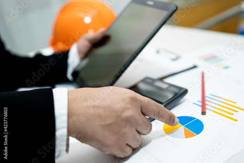 Architect or engineer working project accounting with graph and construction helmet in office, Construction account concept.