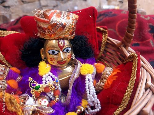 laddu gopal or lord krishna golden idol sitting in bamboo basket with flute closeup shot photo