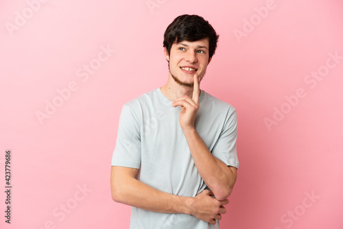 Young Russian man isolated on pink background thinking an idea while looking up