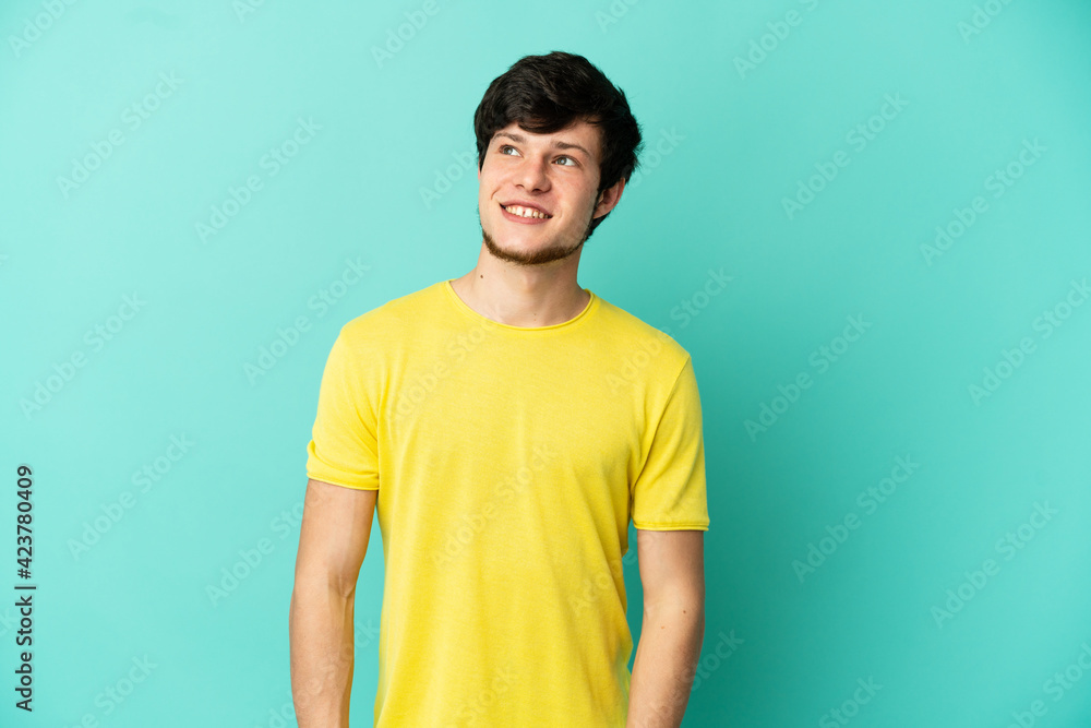 Young Russian man isolated on blue background thinking an idea while looking up Young Russian man isolated on blue background thinking an idea while looking up
