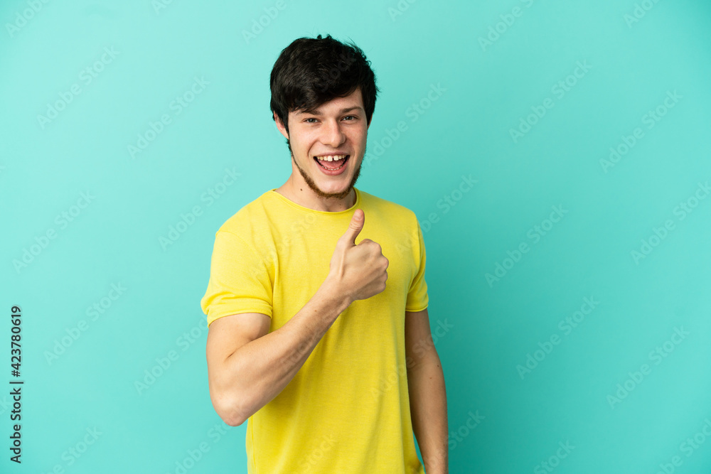 Young Russian man isolated on blue background giving a thumbs up gesture Young Russian man isolated on blue background giving a thumbs up gesture