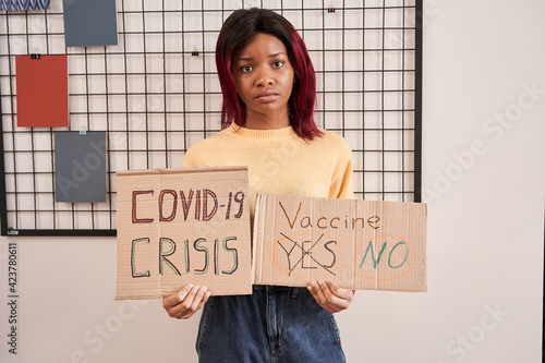 Girl holding posters about covid 19 and vaccine while beckon to something photo