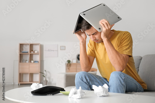 Stressed man with laptop at...