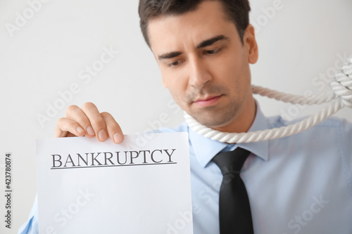 Sad businessman with rope on neck against white background. Bankruptcy concept