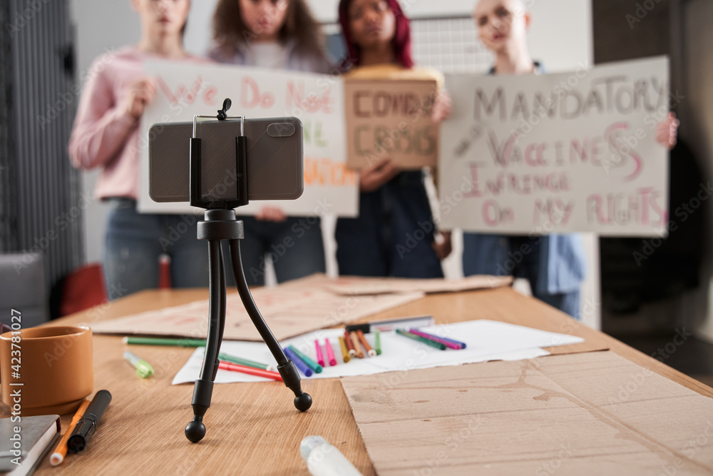 Girls holding posters in front of smartphone and boycotted about vaccine of covid 19 Girls holding posters in front of smartphone and boycotted about vaccine of covid 19