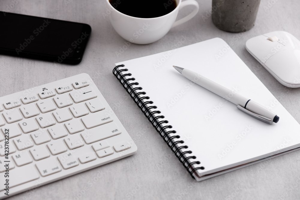 Office table with notebook, coffee cup, keyboard, mouse and mobile phone on marble background. Office table with notebook, coffee cup, keyboard, mouse and mobile phone on marble background.
