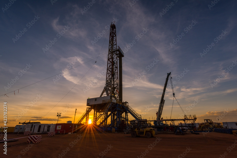 Sunset at drilling rig in oil field of petroleum industry Sunset at drilling rig in oil field of petroleum industry
