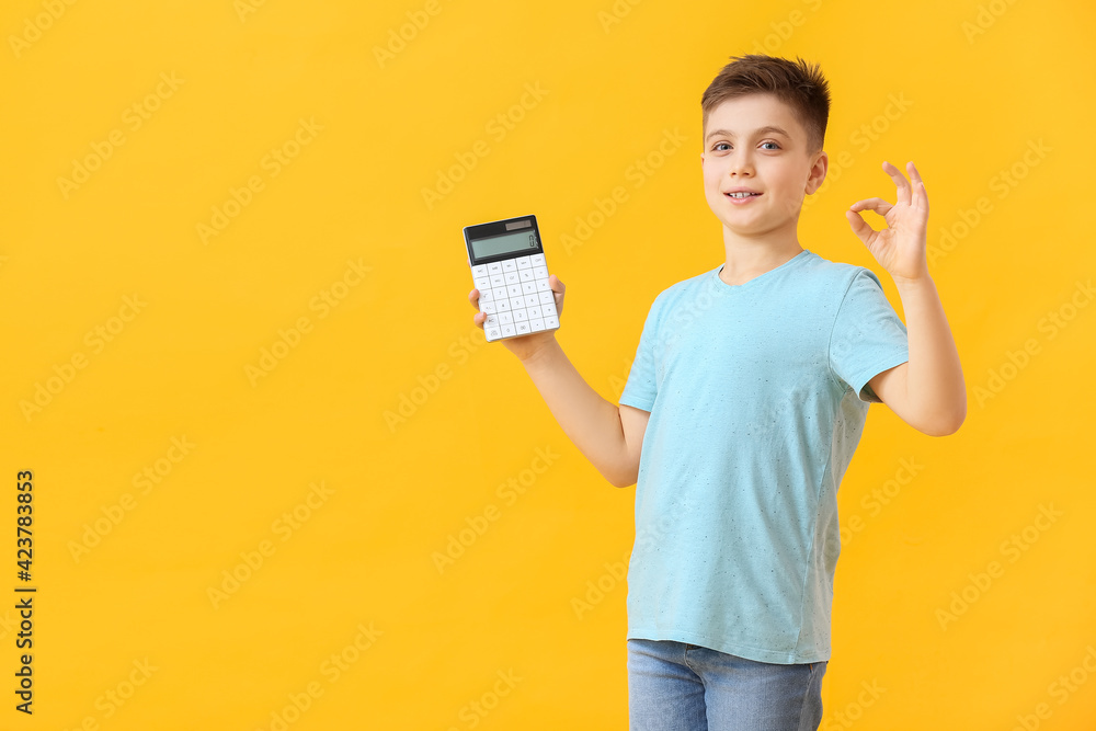 Little boy with calculator showing OK gesture on color background Little boy with calculator showing OK gesture on color background
