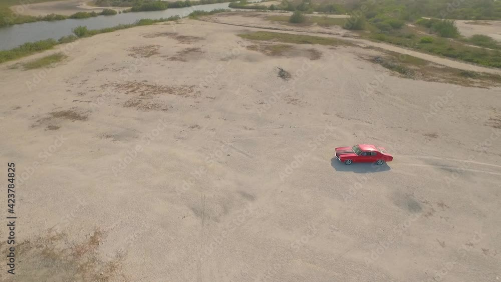 Aerial view of an old American muscle car in a desert during a sunset. Aerial view of an old American muscle car in a desert during a sunset.