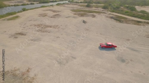 Aerial view of an old American muscle car in a desert during a sunset. photo