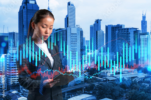 Photography Attractive Asian trader in suit examine her notes to predict the market behavior based on historic data and stock market