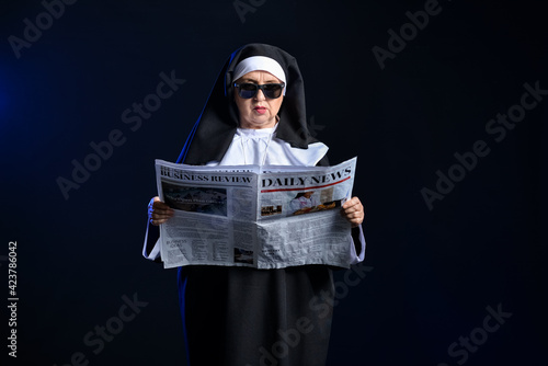 Cool senior nun with newspa...