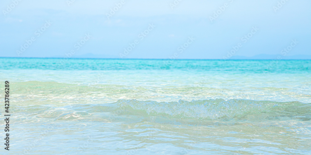 Soft blue ocean wave on clean sandy beach
