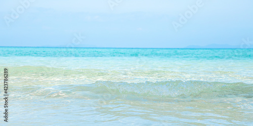 Soft blue ocean wave on clean sandy beach 