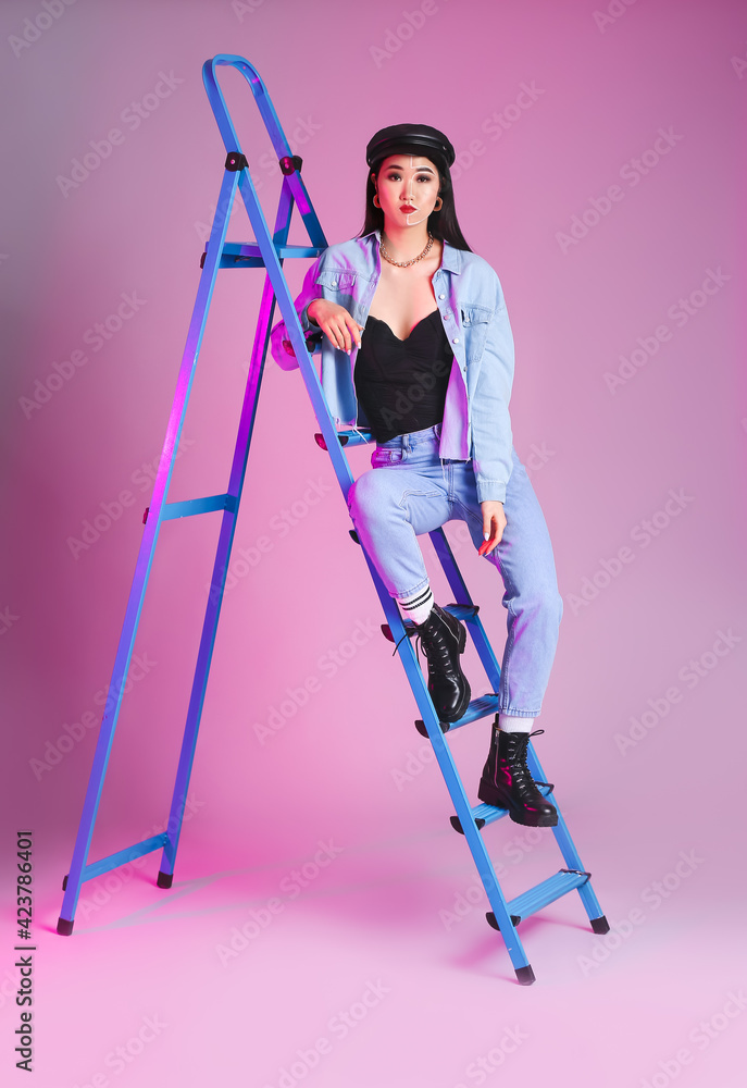 Portrait of stylish Asian woman with ladder on color background Portrait of stylish Asian woman with ladder on color background