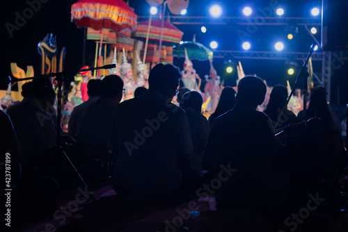 Person group silhouette in ancient musician bank with colorful Khon in background, Ayutthaya province, Thailand 