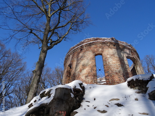 Ruin from bricks with tree covered by snow in sunlight. in Pokoj in Poland. photo