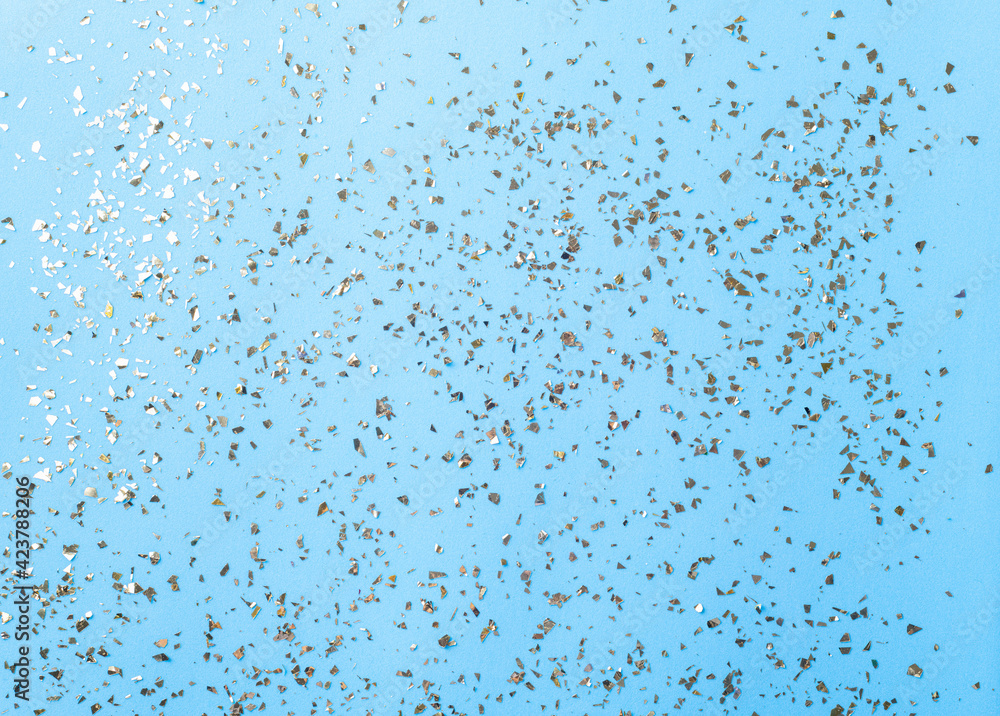 Golden flying sparkles on blue fashion holiday background. Festive backdrop. Texture of golden glitter on blue