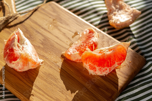 Fresh peeled grapefruit illuminated by sunlight on a wooden board
