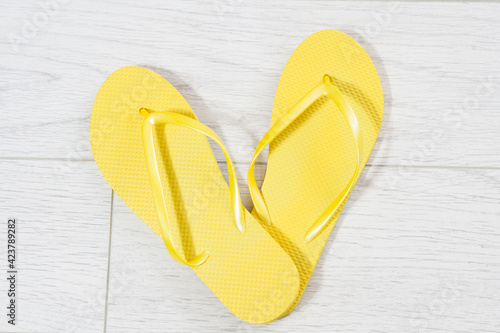 Yellow flip-flops on a white wooden background close up