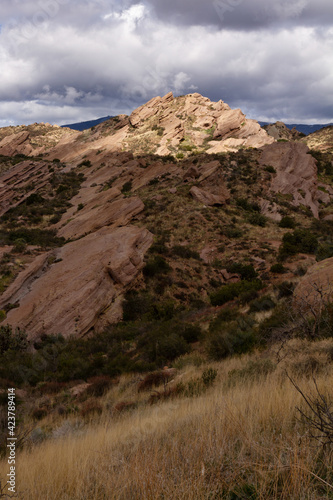 Rock formations under moody skies in the desert. Sunlight breaking through the clouds providing dramatic light on the scene. 