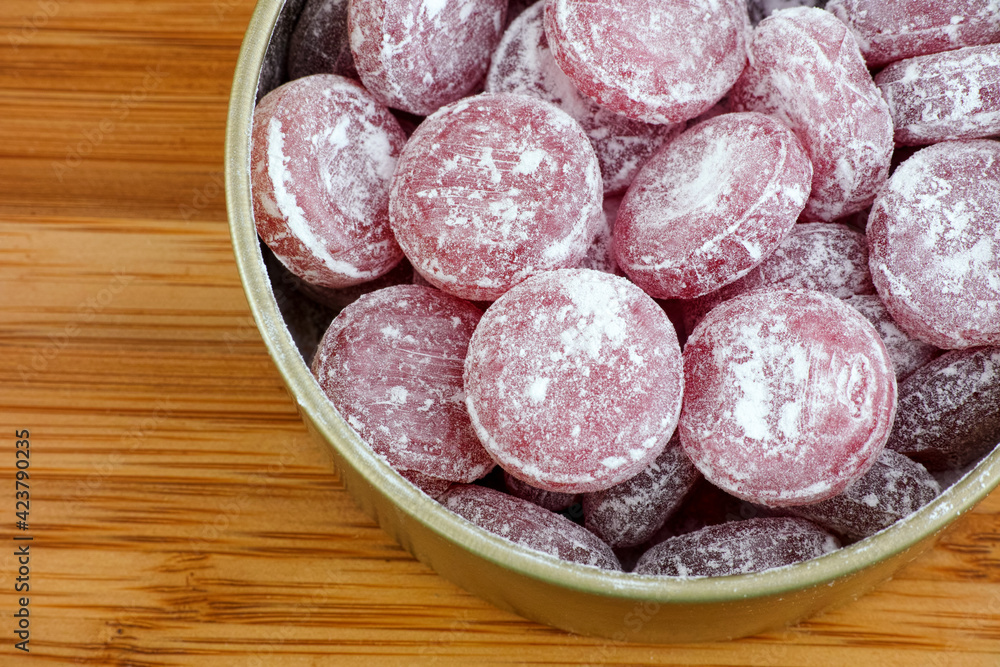 Sour cherry drops. Hard candy with a sour flavor with icing sugar in a tin can.