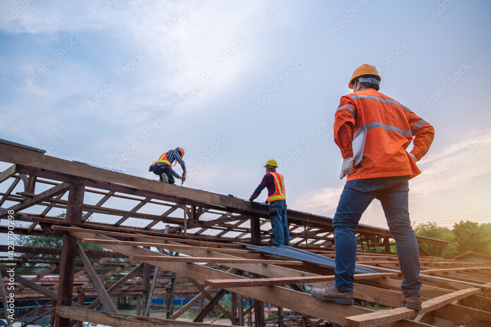 Engineer technician watching team of roofer working on roof structure of building in construction site, Roof metal sheet construction concept. Engineer technician watching team of roofer working on roof structure of building in construction site, Roof metal sheet construction concept.