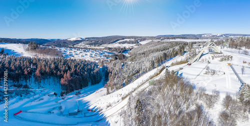 Saint George ski jump and ski slopes of Winterberg ski lift carousel photographed from the air. Panorama image of deserted winter sports area. photo
