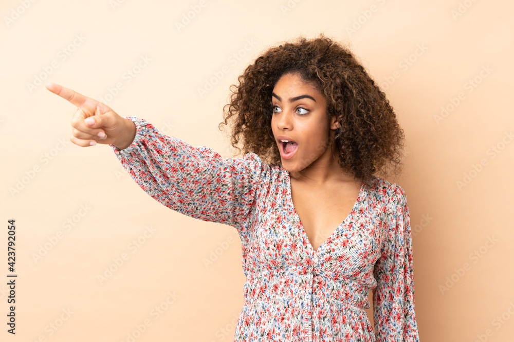 Young African American woman isolated on beige background pointing away Young African American woman isolated on beige background pointing away